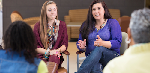 A parent and teacher sitting together at a school table, reviewing documents at an IEP meeting — the kind of collaborative conversation myABCIEP helps families prepare for